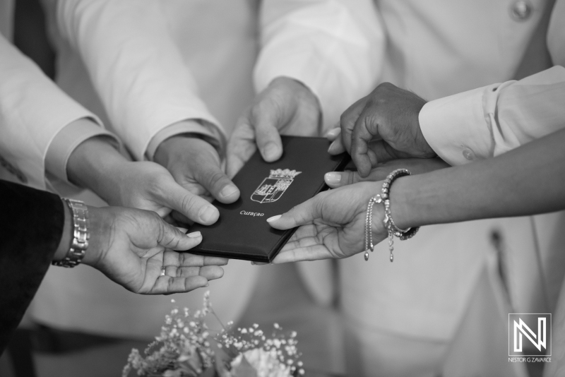 Bride, groom, officiant and witnesses hands taking the family book