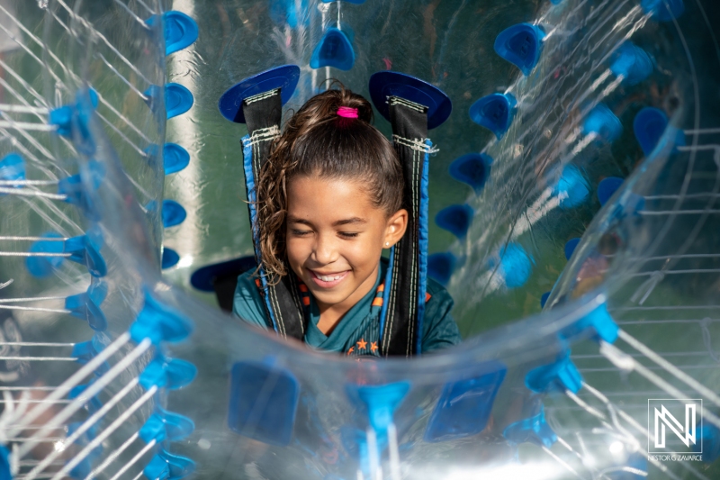 Child enjoying a birthday celebration inside a zorb ball at a fun location in Curacao during a sunny afternoon