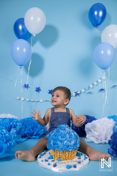 Celebrate a joyful birthday in Curacao with a young child enjoying a blue-themed cake surrounded by festive decorations and balloons