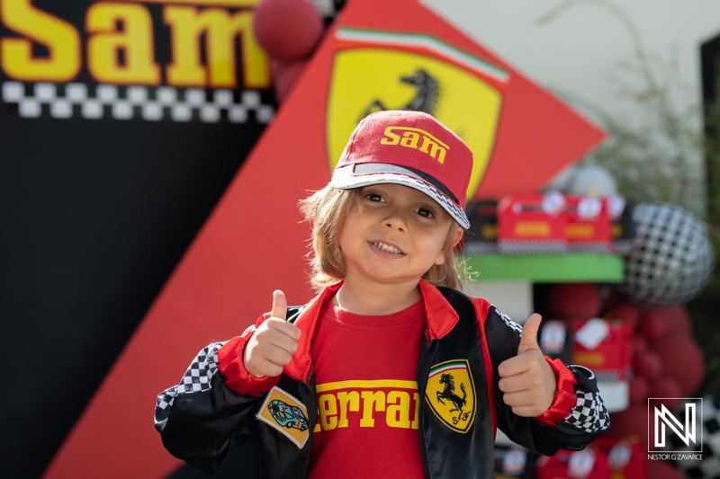 Celebrating a birthday in Curacao with a young race car fan dressed in Ferrari attire enjoying the festivities