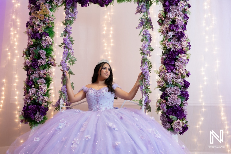 Birthday celebration in Curacao featuring a young girl on a floral swing adorned with purple flowers and sparkling lights