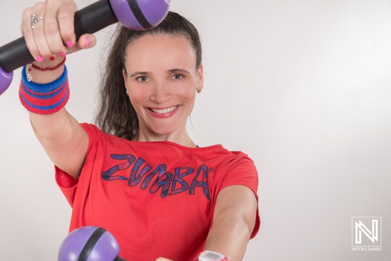 Curacao fitness instructor promoting an active lifestyle with colorful weights and vibrant attire in a studio environment