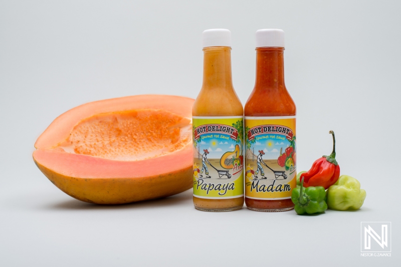 Hot sauces made from fresh papaya and peppers showcased with a sliced papaya in a bright setting in Curacao