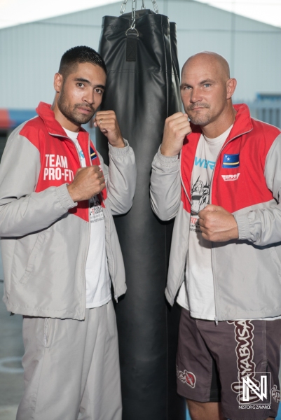 Two athletes pose confidently beside a heavy bag during a training session in Curacao showcasing teamwork and dedication