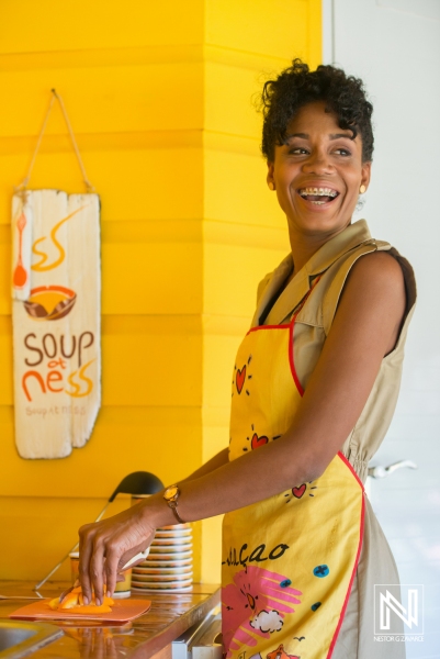 Smiling woman serving soup in a vibrant eatery in Curacao during midday hours