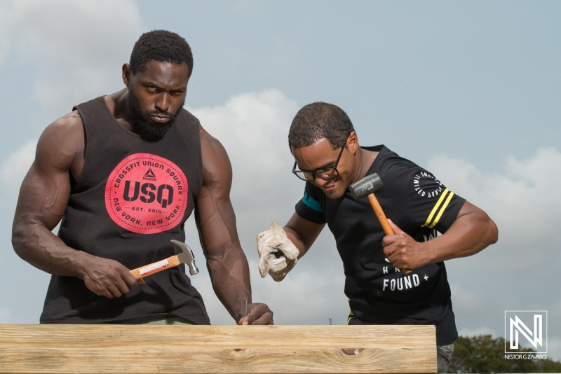 Two men engaged in construction work in Curacao, showcasing strength and teamwork while building a wooden structure on a sunny day