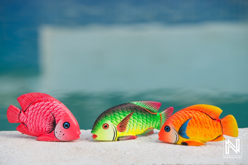 Colorful fish figurines represent the vibrant marine life of Curacao in a lively commercial setting by the water