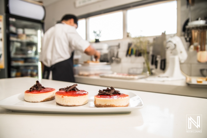 Delicious desserts being prepared in a bright kitchen in Curacao with vibrant cheesecakes topped with chocolate and fruit