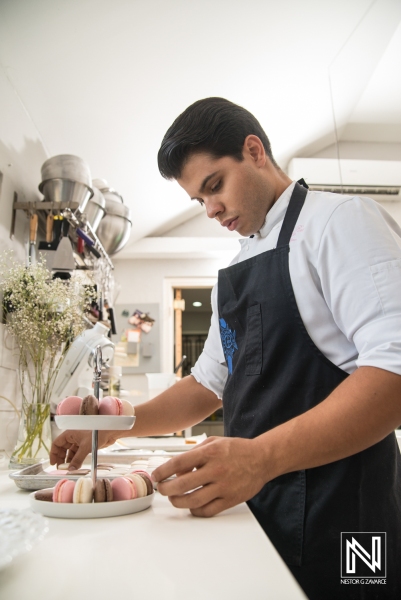 Pastry chef preparing colorful macarons in a modern culinary space in Curacao during daylight hours