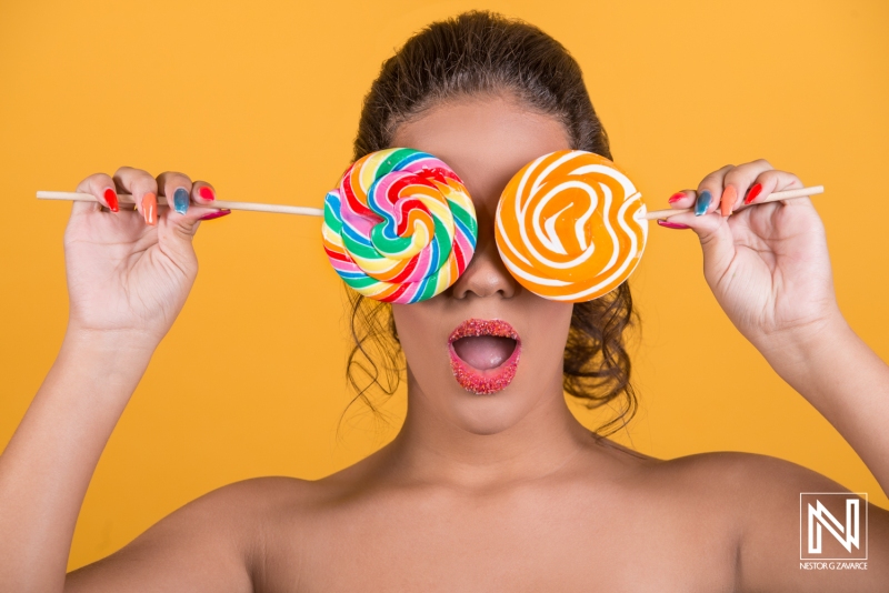 Curacao carnival-inspired commercial featuring vibrant girl holding colorful lollipops in front of her face against a bright yellow backdrop