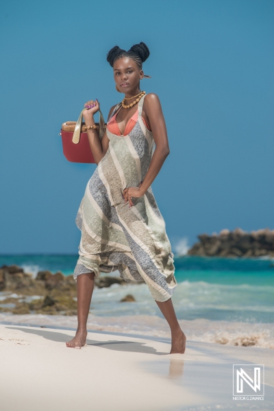 Model showcases vibrant summer fashion while enjoying a sunny beach in Curacao with crystal-clear waters and soft sand