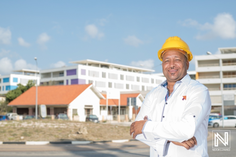 Construction professional poses in Curacao's commercial district under clear skies during daytime