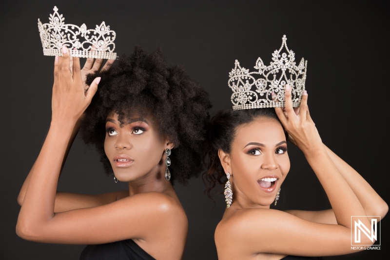 Two women showcase elegant crowns, celebrating beauty and confidence in a commercial setting in Curacao