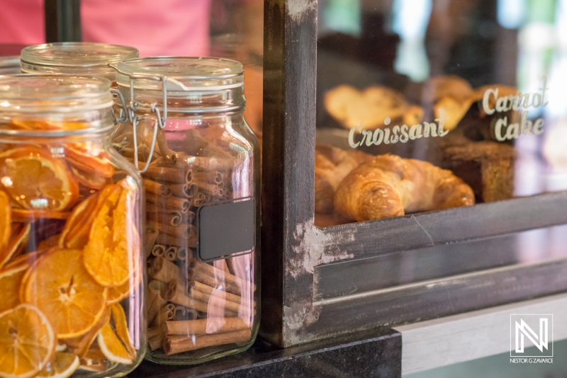 Colorful jars of dried fruits and spices alongside freshly baked pastries in a Curacao bakery display