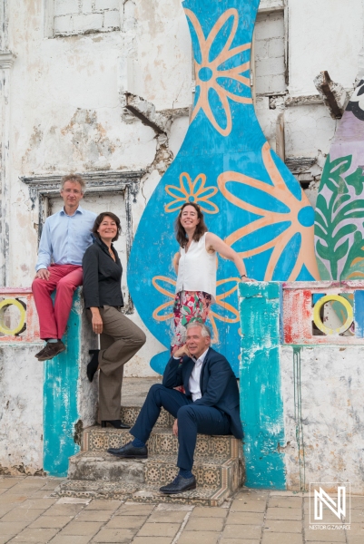 Group of professionals posing in front of vibrant mural in Curacao during a business gathering