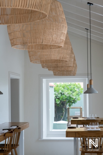 Modern dining interior with woven lamps showcasing scenic views in Curacao's coastal restaurant during daytime