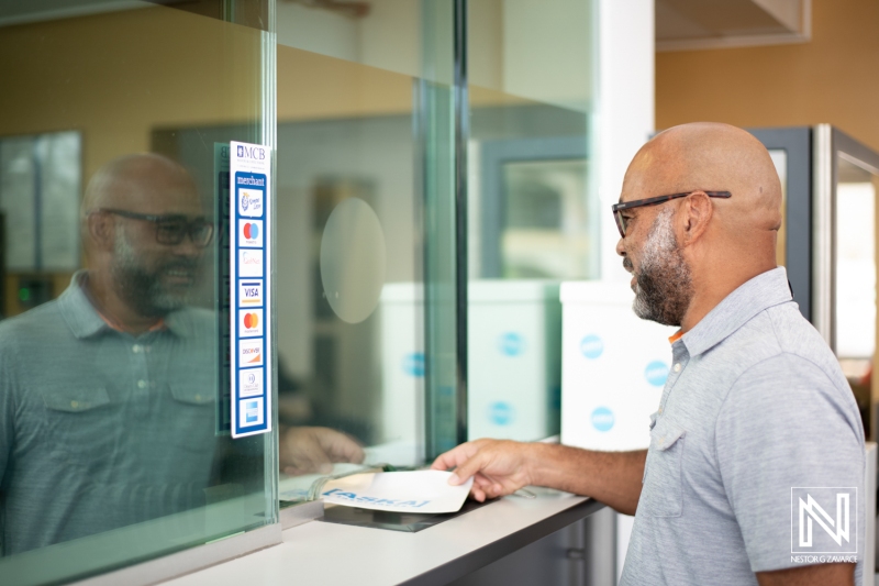 Man engaging in a commercial transaction at a service window in Curacao during daytime hours