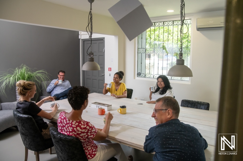 Team members gather for a productive meeting in a cozy workspace in Curacao, discussing ideas over coffee and enjoying a collaborative atmosphere