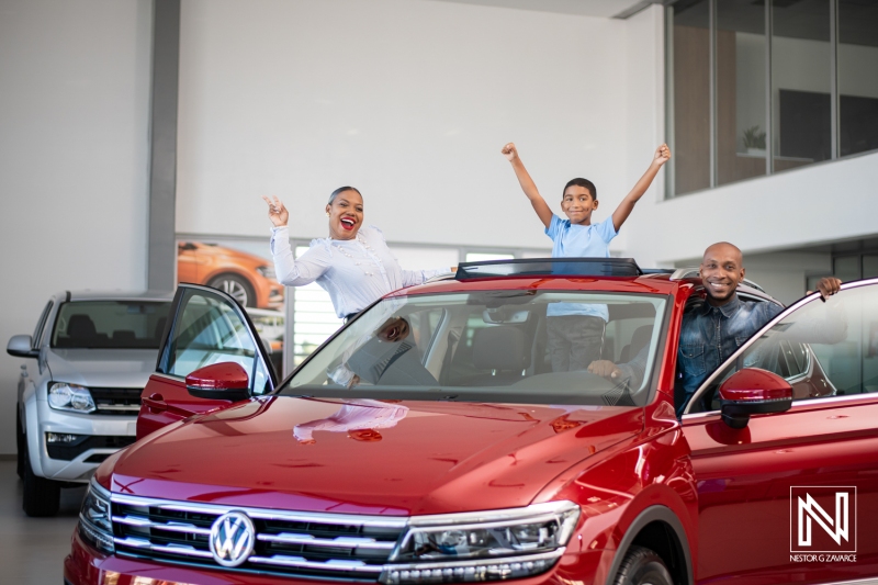 Family celebrates new car purchase in a modern showroom in Curacao, showcasing joy and excitement during their shopping experience