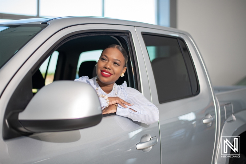 Smiling woman enjoying a day out in a modern pickup truck in Curacao's vibrant commercial setting