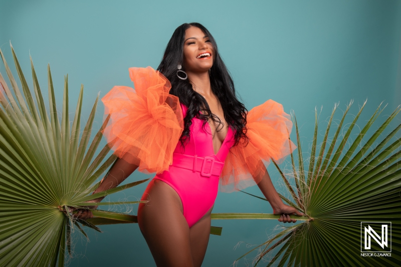 Colorful summer fashion shoot in Curacao featuring a joyful model with palm leaves