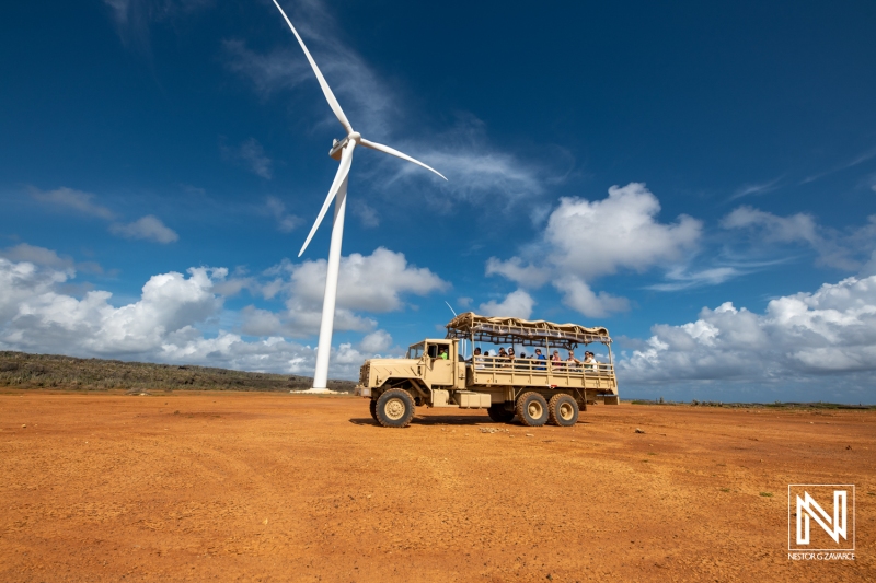 Group of tourists enjoying an off-road expedition near a wind turbine in Curacao while surrounded by natural scenery during daytime