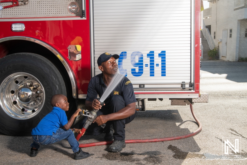 Firefighter demonstrates safety techniques with child in Curacao during community outreach event to promote fire prevention