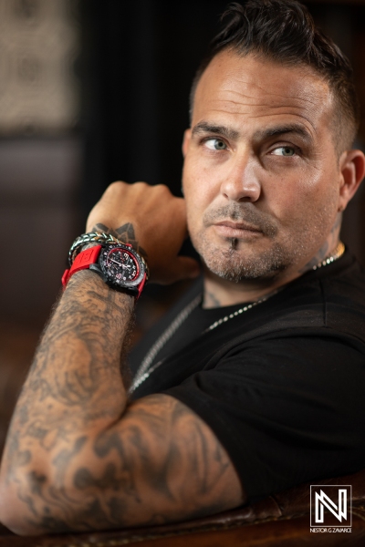 Portrait of a man with tattoos showcasing his stylish watch in a modern interior in Curacao during a commercial shoot