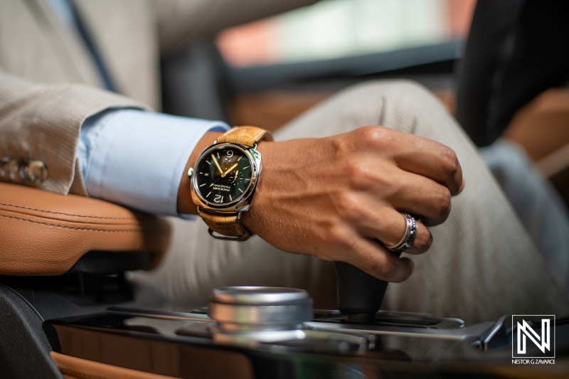 Stylish man showcases elegant watch while taking control of luxury vehicle in Curacao's vibrant atmosphere