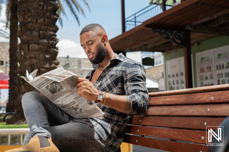 Reading a newspaper casually in a vibrant outdoor space in Curacao during sunny daylight hours