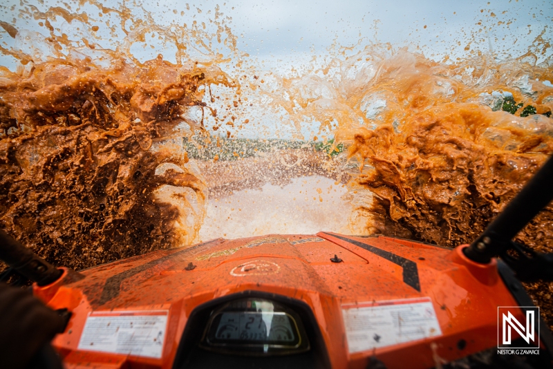 Experience thrilling off-road adventure in Curacao while riding an ATV through muddy trails with splashes of water