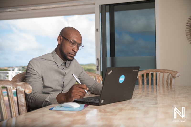 Professional man working on laptop at modern table in Curacao with a scenic view in the background