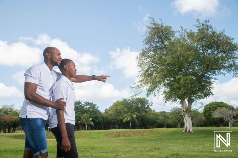 Father and son enjoy a sunny day in Curacao, pointing at a distant tree while exploring the lush landscape