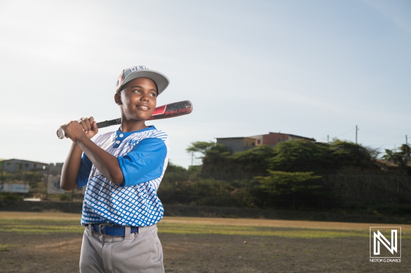 Youth baseball player prepares to swing bat in Curacao during a sunny day, showcasing talent and enthusiasm for the sport in a vibrant community setting