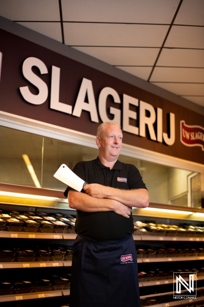 Master butcher stands proudly in his shop showcasing skill in the heart of Curacao with an inviting atmosphere and expert craftsmanship