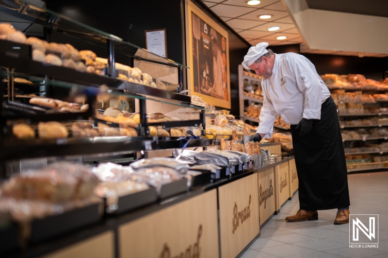 Bakery worker arranging freshly baked goods in a commercial space in Curacao during the day