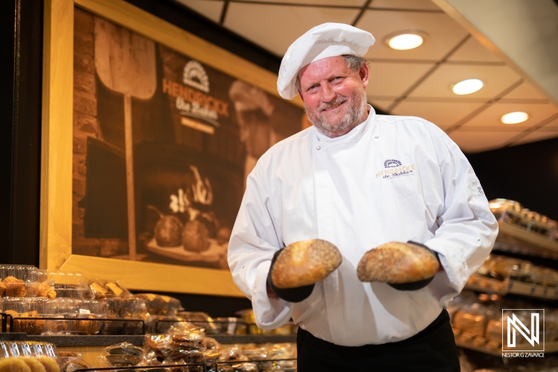 Baker presenting fresh bread at a commercial bakery in Curacao during a busy morning