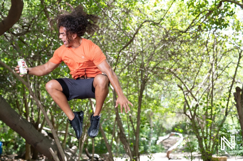 Energetic man jumping in lush nature while enjoying a refreshing drink during commercial shoot in Curacao