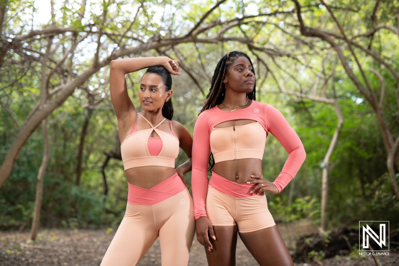 Two women showcase activewear in a natural setting, embodying fitness and confidence in Curacao's lush greenery during daylight