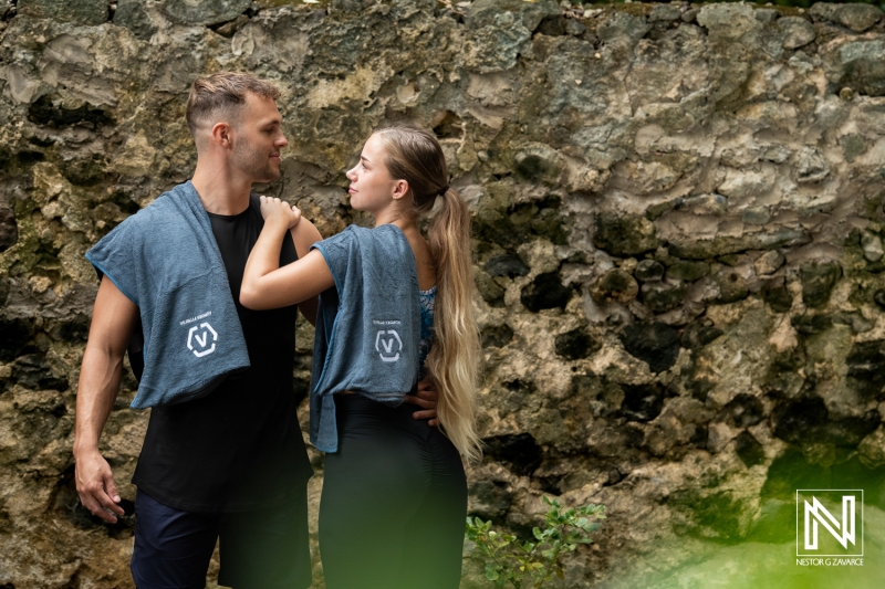 Couple enjoys a moment together against a textured stone wall in Curacao during a brand promotion event focused on lifestyle and fitness