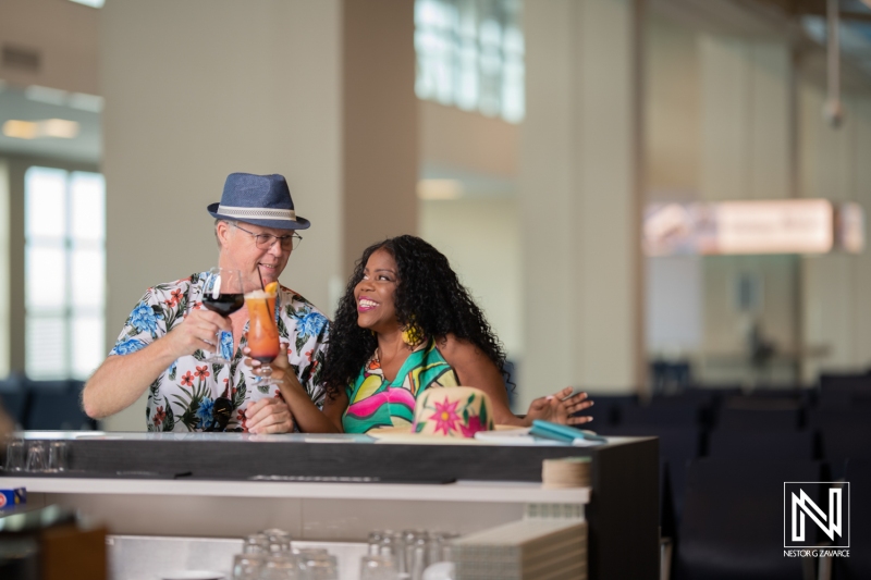 Couple enjoys tropical drinks at a lively bar in Curacao during a sunny day, highlighting the vibrant atmosphere of the Caribbean