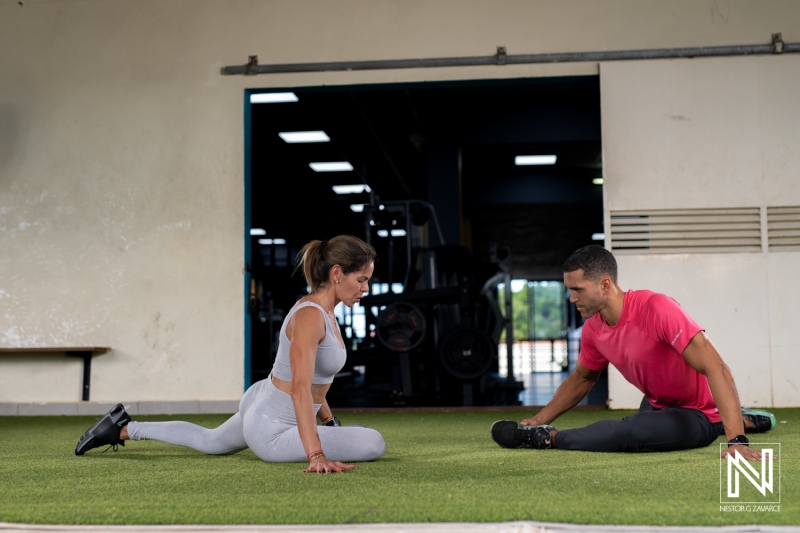 Fitness training session in Curacao featuring male and female athletes engaged in stretching exercises on a green surface