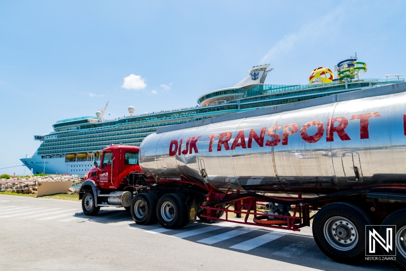 Transport truck delivers supplies to the bustling port of Curacao while cruise ship passengers enjoy their vacation experience