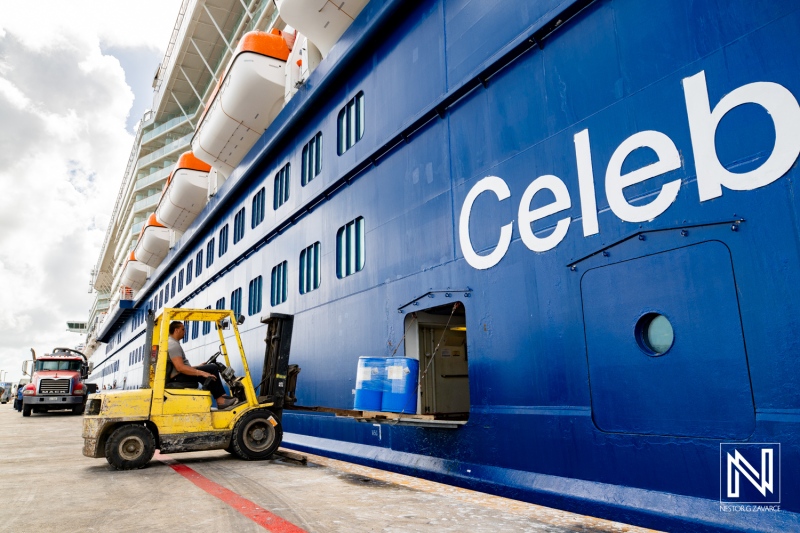 Forklift operator unloads cargo at cruise ship docked in Curacao commercial harbor during daytime operations