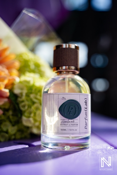 Product photoshoot for ParfumLab Curacao showcases a perfume bottle on a purple surface with flowers in the background