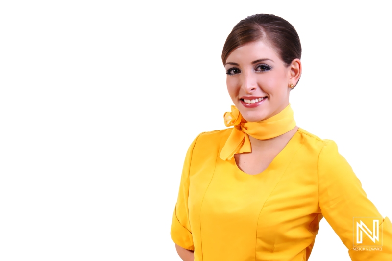 Brightly Dressed Female Attendant Poses Cheerfully, Showcasing Warm Smile and Professional Demeanor, Highlighting Vibrant Uniform and Stylish Neck Scarf in a Studio Setting