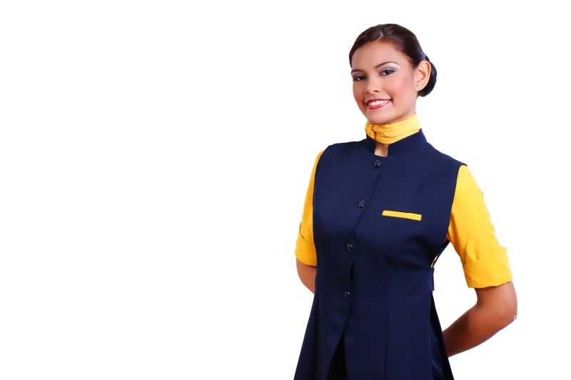 Airline Attendant Standing Confidently Against a Plain Background, Showcasing a Professional Uniform in Shades of Blue and Yellow, Likely During a Promotional Event or Training Session