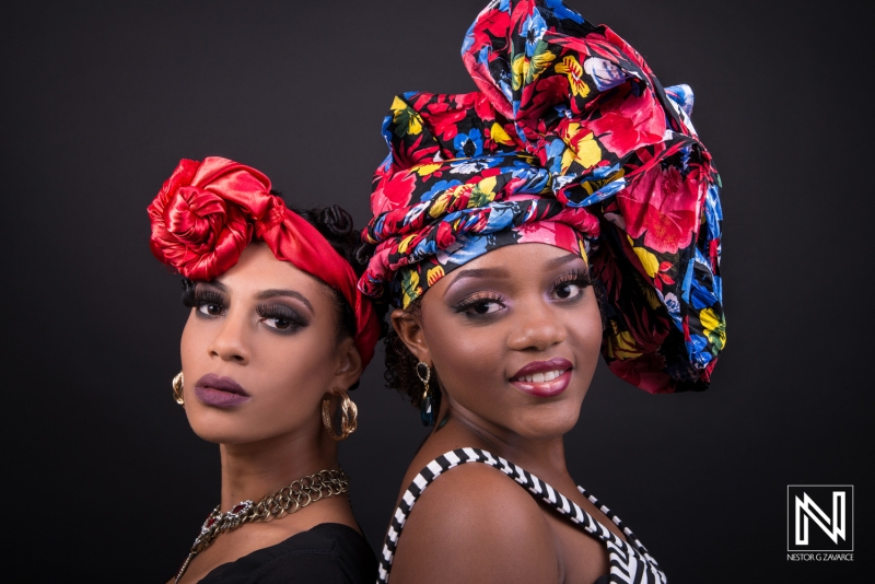 Two Women Showcase Vibrant Headwraps and Bold Makeup Against a Dark Backdrop, Celebrating Culture and Style During a Studio Photoshoot