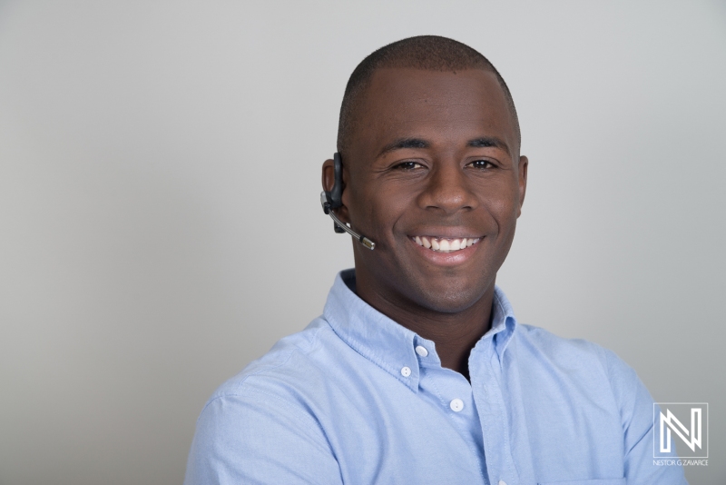 A Smiling Young Man in a Blue Shirt Wearing a Headset, Representing Customer Service or a Professional Business Environment Indoors