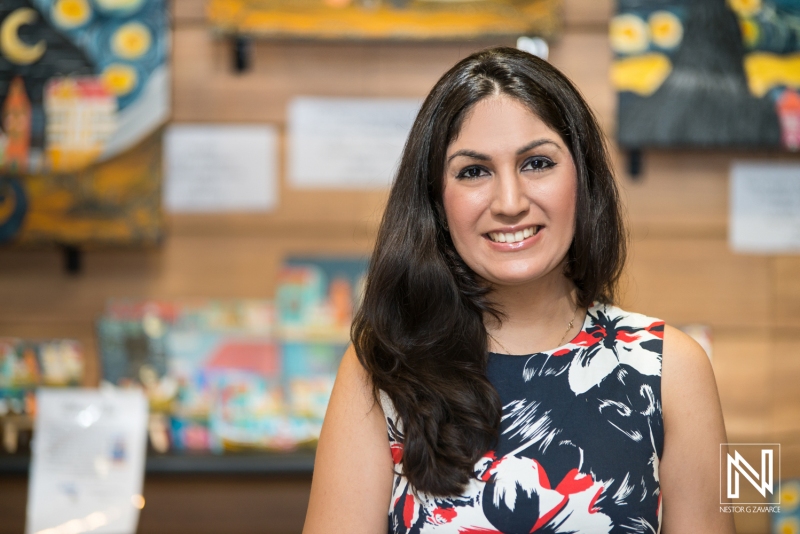 A Woman Smiles Warmly While Standing in a Colorful Art Gallery Filled With Vibrant Artworks During the Afternoon, Highlighting a Creative Atmosphere and Artistic Spirit